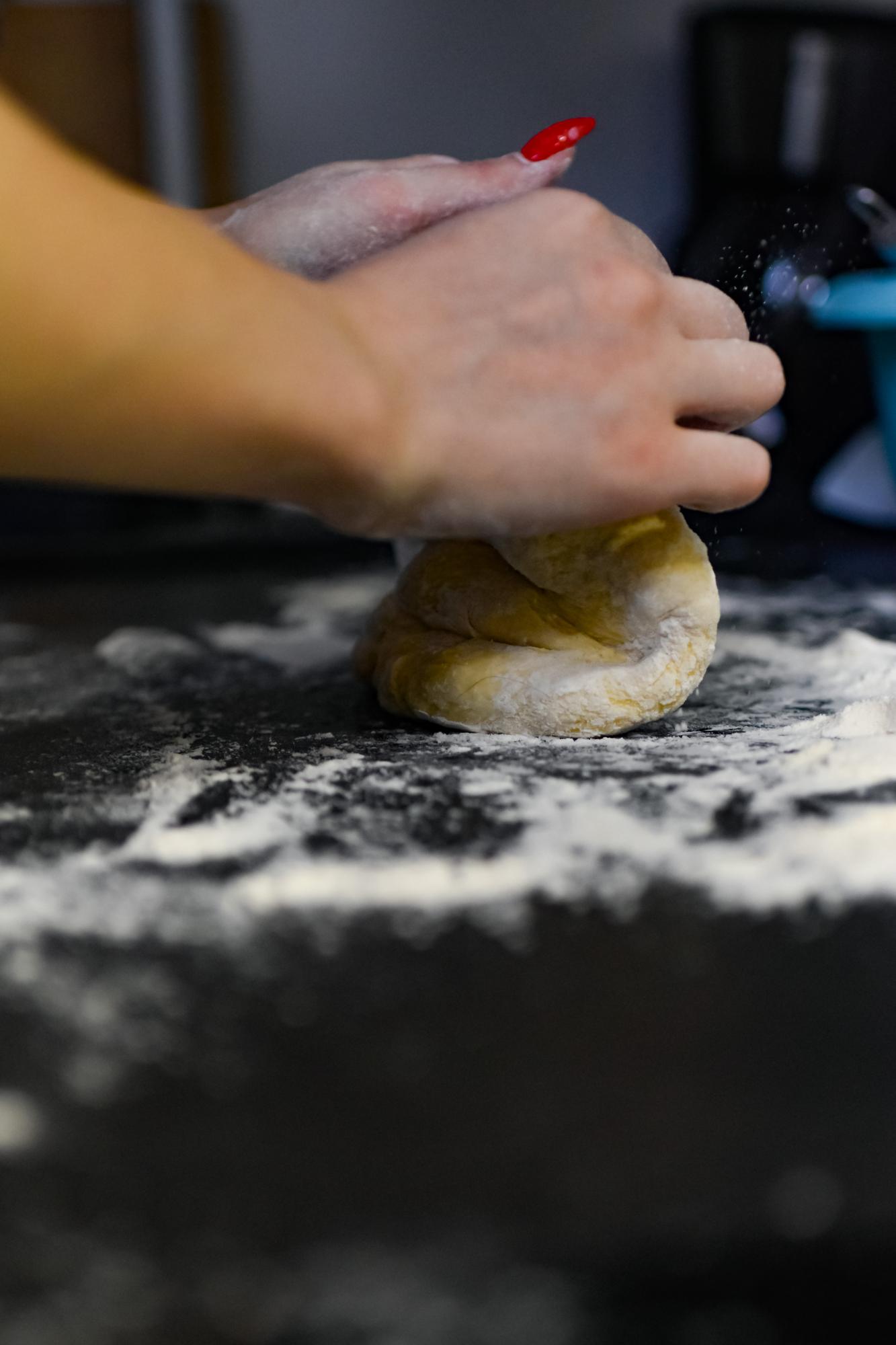 Dettaglio di mani che impastano in cucina